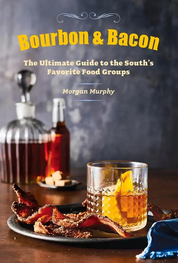 Books on Bourbon The image features the cover of the hardcover book "Bourbon & Bacon: The Ultimate Guide To the South's Favorite Food Groups" by Morgan Murphy. The cover displays a stylish and appetizing setup with a glass of bourbon and a plate of bacon, symbolizing the book's theme.